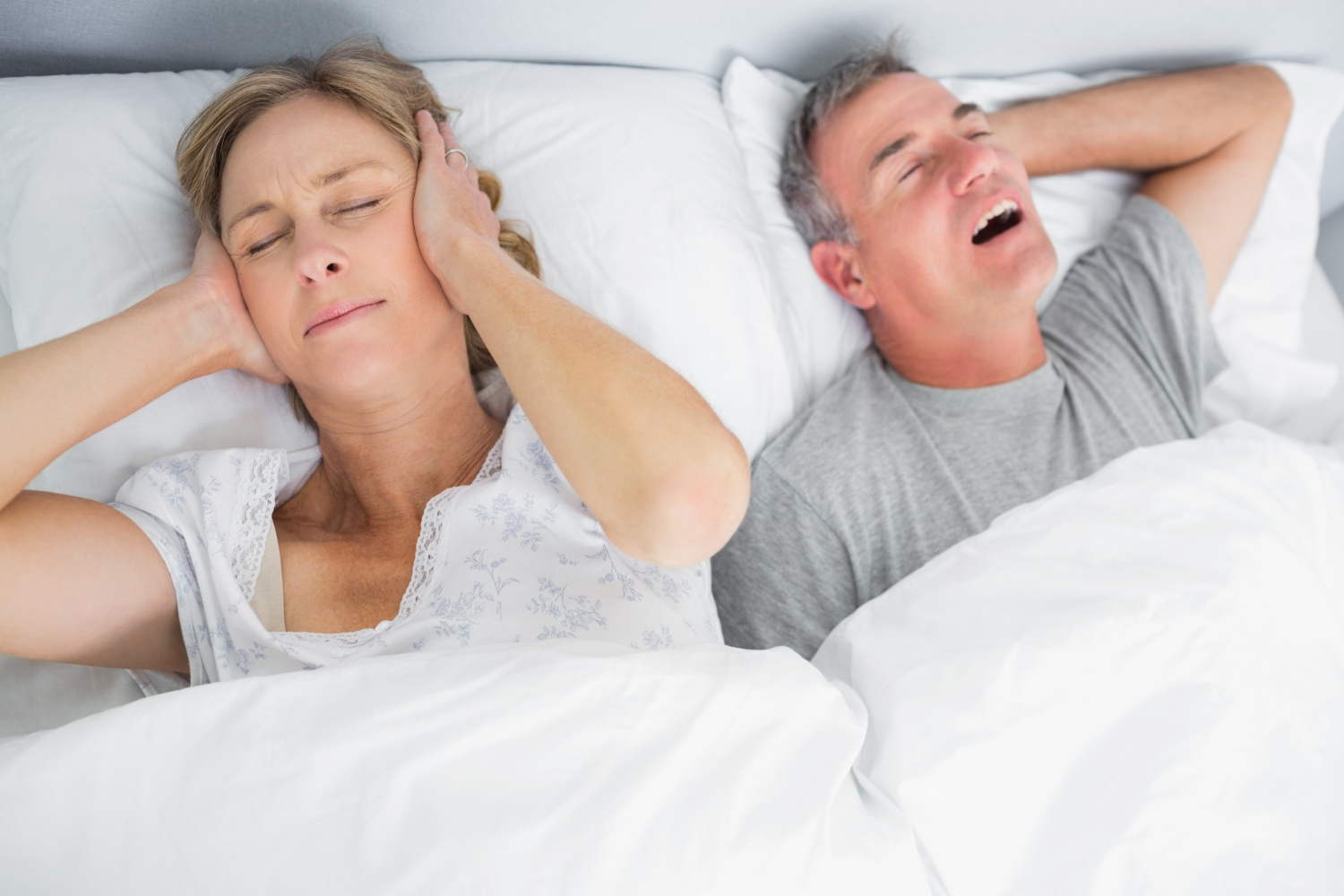 coppia a letto: lui russa e lei si tappa le orecchie con le mani